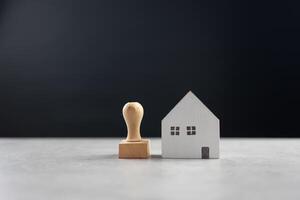 Rubber stamp and model home on table with black background photo