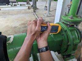 hombre trabajador medida vibración motor y bomba en poder planta proyecto. el foto es adecuado a utilizar para industria antecedentes fotografía, poder planta póster y electricidad contenido medios de comunicación.