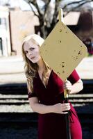 Blond Caucasian Woman In Red Dress Holding On To Yellow Sign photo