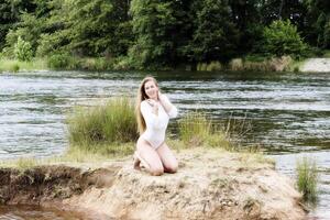 Caucasian Teen Woman Kneeling Along River In White Leotards photo