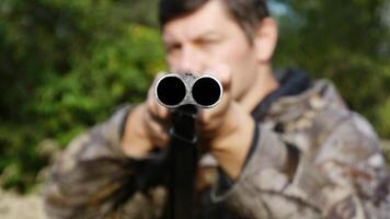 Hunter with a gun in the woods. Hunter directs the gun at the camera video