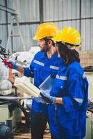 Mecánico del equipo de ingenieros que usa un brazo robótico controlador de computadora para soldar acero en el taller de la fábrica de acero. software de programación de robots industriales para tecnología de fabricación automatizada foto