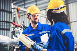 Engineers team mechanic using computer controller Robotic arm for welding steel in steel factory workshop. Industry robot programming software for automated manufacturing technology photo