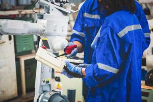 Engineers team mechanic using computer controller Robotic arm for welding steel in steel factory workshop. Industry robot programming software for automated manufacturing technology photo