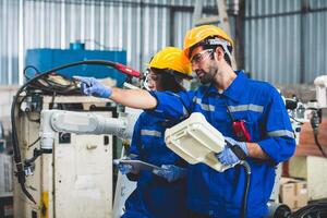 Engineers team mechanic using computer controller Robotic arm for welding steel in steel factory workshop. Industry robot programming software for automated manufacturing technology photo