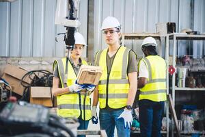 Mecánico del equipo de ingenieros que usa un brazo robótico controlador de computadora para soldar acero en el taller de la fábrica de acero. software de programación de robots industriales para tecnología de fabricación automatizada foto