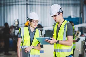 Engineers mechanic team holding check list on clipboard and pen in steel factory workshop. Industry robot programming software for automated manufacturing technology photo