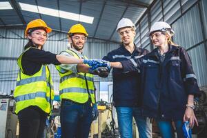 Engineers team mechanic making pile of hands in steel factory workshop. Industry robot programming software for automated manufacturing technology photo