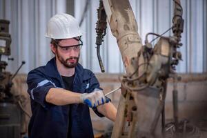 ingenieros equipo mecánico reparar robótico brazo para soldadura acero en acero fábrica taller. industria robot programación software para automatizado fabricación tecnología foto