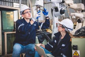 Mecánico del equipo de ingenieros que usa un brazo robótico controlador de computadora para soldar acero en el taller de la fábrica de acero. software de programación de robots industriales para tecnología de fabricación automatizada foto