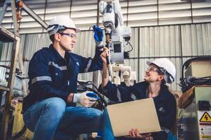 Mecánico del equipo de ingenieros que usa un brazo robótico controlador de computadora para soldar acero en el taller de la fábrica de acero. software de programación de robots industriales para tecnología de fabricación automatizada foto