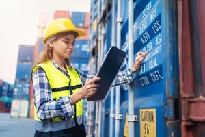 Women Engineer wears PPE checking container storage with cargo container background at sunset. Logistics global import or export shipping industrial concept. photo