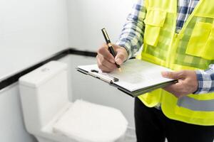 el inspector o ingeniero está inspeccionando la construcción y el aseguramiento de la calidad de la nueva casa usando una lista de verificación. ingenieros o arquitectos o contratistas trabajan para construir la casa antes de entregársela al propietario foto