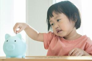 ahorrar dinero. niños poniendo monedas para ahorrar. riqueza, finanzas, seguros, inversiones, educación, futuro, planificar la vida, aprender, banca, familia, salud, salud y seguros de accidentes. foto