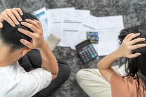 Stressed and headache asian couple with large bills or invoices no money to pay to expenses and credit card debt. shortage, Financial problems, mortgage, loan, bankruptcy, bankrupt, poor, empty wallet photo