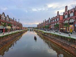 Jacarta, Indonesia - enero 30 2024 tiendas en el borde de el río con barcos paso por con edificios con un pequeño europeo Amsterdam foto