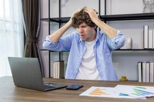 Caucasian man freelancer is having serious error problem with program while working at home having headache and frustration about online task for accountant, auditor, programer and broker occupation photo