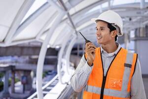 indio hombre ingeniero es utilizando walkie película sonora mientras inspeccionando el construcción proyecto para moderno arquitectura y real inmuebles desarrollo industria foto