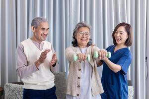 Senior couple get medical service visit from caregiver nurse at home while dumbbell exercising muscle strength in pension retirement center for rehabilitation and longevity post recovery process photo