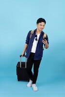 Handsome Asian male tourist wear casual clothes hold suitcase mobile cell phone isolated on pastel blue color background. photo