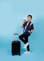 Excited handsome Asian male tourist wearing casual clothes holding passport ticket standing isolated on light blue background. air travel concept photo