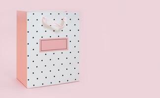 White pink with polka dot package bag for shopping or gift on pink background. Holiday, March 8, International Women's and Mother's Day, Valentine, wedding, sale. Copy space photo