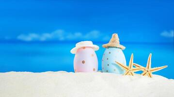 Pink and blue with polka dot eggs with hat with starfish on beach with sea on sunny day. Easter, travel, vacation. Copy space photo