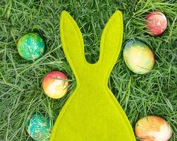 Green felt rabbit with colored eggs. Easter. Copy space photo