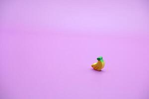 Mini banana toy isolated on purple background. purple background with banana toys. photo