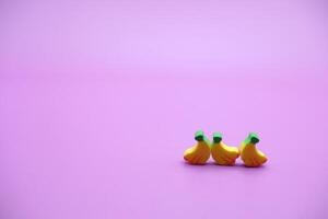 Mini banana toy isolated on purple background. purple background with banana toys. photo