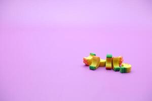 Mini banana toy isolated on purple background. purple background with banana toys. photo