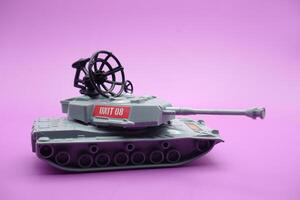 gray toy tank isolated on purple background. imitation of a tank commonly used by the armed forces. photo