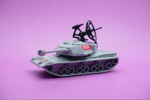 gris juguete tanque aislado en púrpura antecedentes. imitación de un tanque comúnmente usado por el armado efectivo. foto