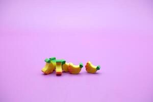 Mini banana toy isolated on purple background. purple background with banana toys. photo