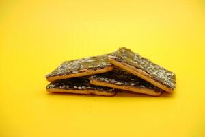 cracker biscuits with chocolate coating. biscuit cracker isolated on yellow background. photo