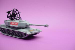 gray toy tank isolated on purple background. imitation of a tank commonly used by the armed forces. photo