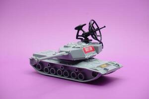 gray toy tank isolated on purple background. imitation of a tank commonly used by the armed forces. photo