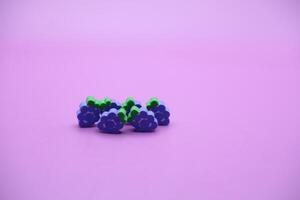 purple background with grape toys. Grape-shaped eraser isolated on purple background. photo