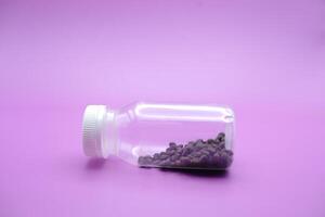 kale seeds in a clear plastic bottle. kale seeds isolated on a purple background. photo