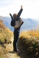 a child standing on a trail with their arms up photo