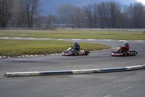 two people riding go-karts on a track photo