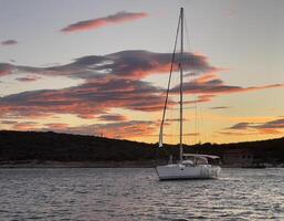 a sailboat is anchored in the water at sunset photo