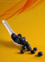 a spoon filled with blueberries on a yellow background photo