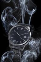 un reloj es rodeado por fumar en un negro antecedentes foto