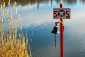 an alarm bell with sos in front of a lake photo