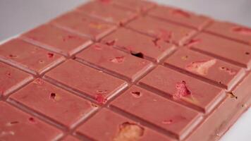 A bar of pink ruby chocolate with freeze-dried strawberries and almonds close-up. A healthy dessert based on berries and nuts video