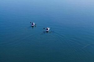 Folsom, CA, 2010 - Two Men Paddling Away From Camera On Blue Water With Wake photo