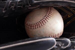 Closeup of old baseball in black glove photo