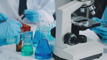 Health care researchers working in life science laboratory. Young female research scientist and senior male supervisor preparing and analyzing microscope slides in research lab. video