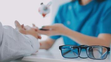 close up of asian female doctor wearing face mask is showing eyeball model and explaining about eyes disease to elder senior man patient in hospital video